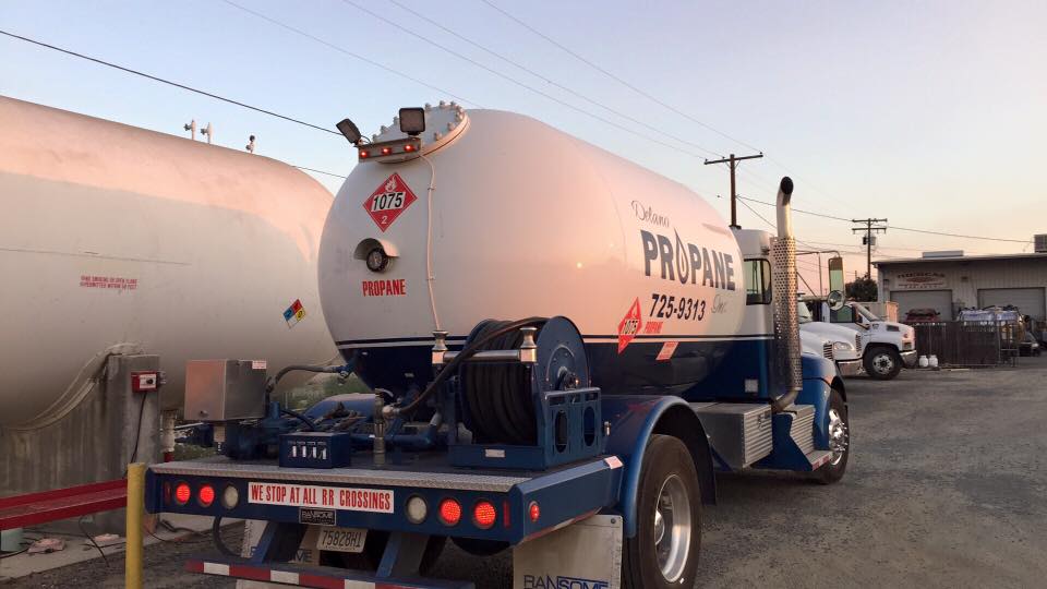 Rear view of a Delano Propane tanker truck at the yard at dusk with hose reel and 1075 placard